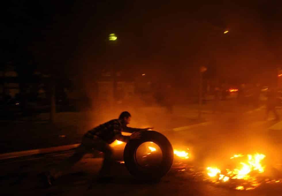 Un piquete coloca un neumático en una barricada puesta en Mercabarna, Barcelona.