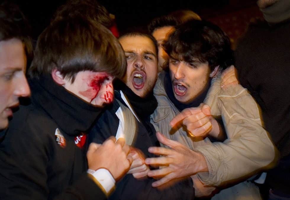 Varios jóvenes ayudan a un compañero que tiene la cara ensangrentada después de ser golpeado por la policía durante la huelga nacional
