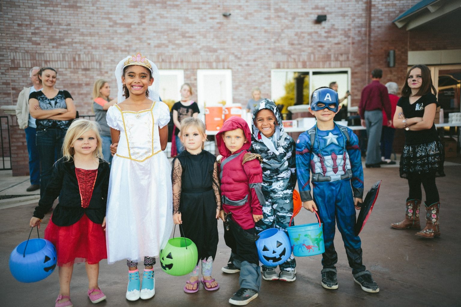 Las tendencias en fiestas para niños  children standing while holding Jack 'o lantern and wearing costume