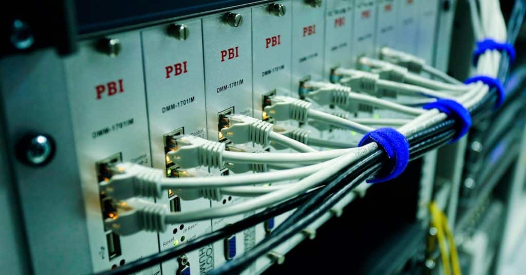 Cómo funciona una CDN y qué beneficios tiene para tu sitio web Close-up of ethernet cables connected to a network switch panel in a data center.